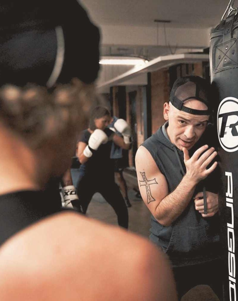 Experienced boxing coach providing hands-on support during training at FighterFit gym in London.